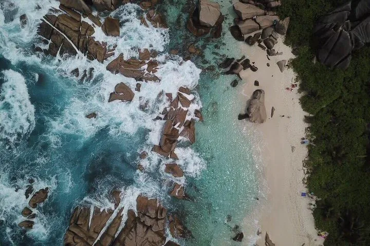 Aerial view of waves crashing against rocks at a white sand beach