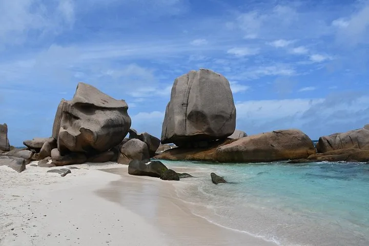Massive granite boulders resting on the sandy shore of Anse Marron
